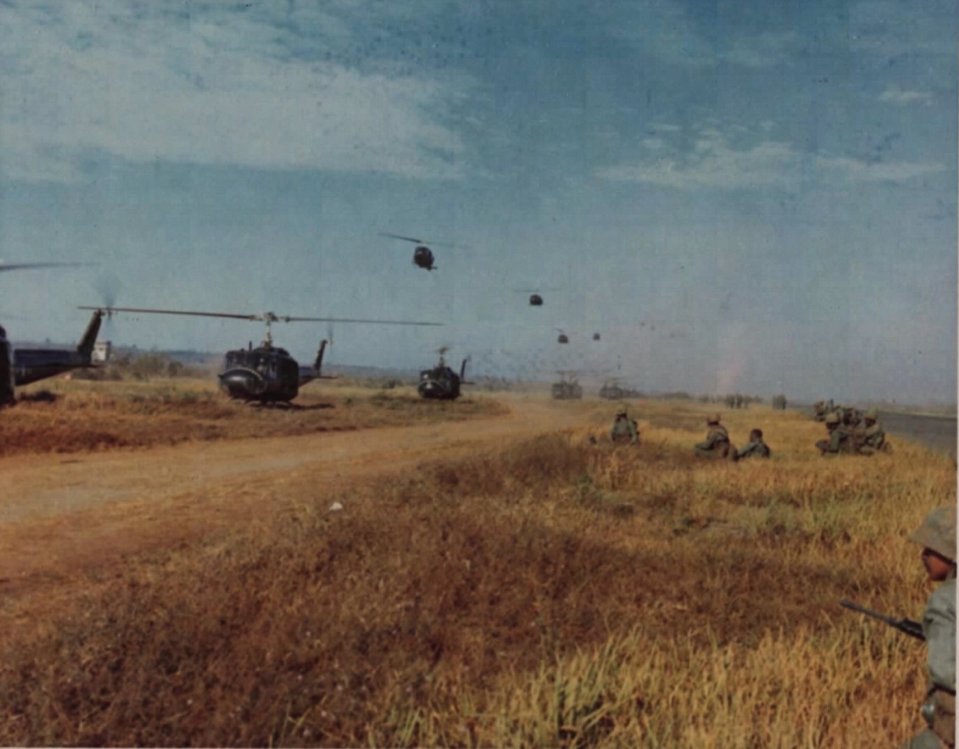 Soldiers running toward helicopters on an open field