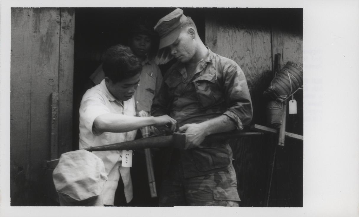 A highland man showing an American Marine how to hold a crossbow