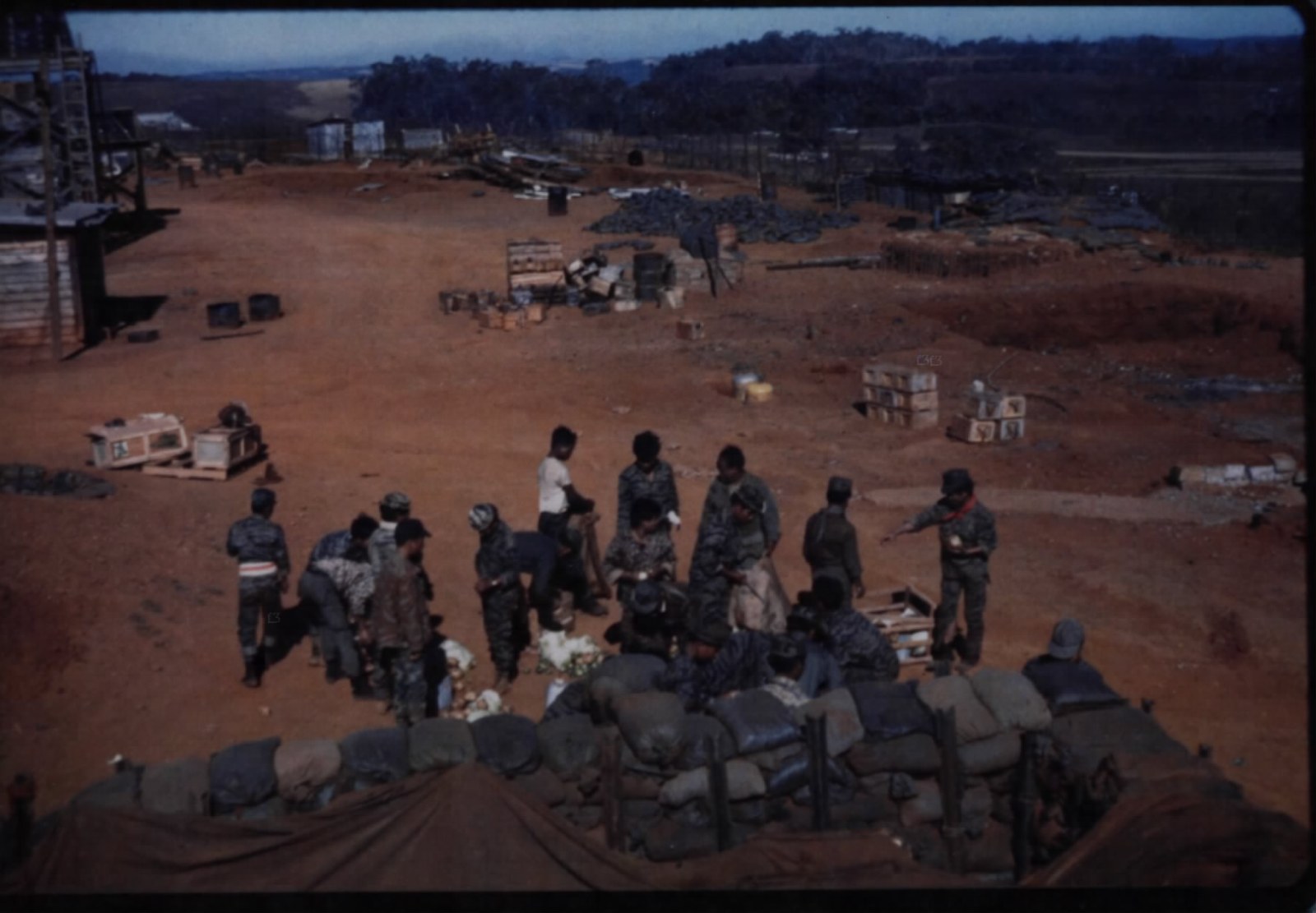 Soldiers in a camp of sandbags and wire on a dry plain