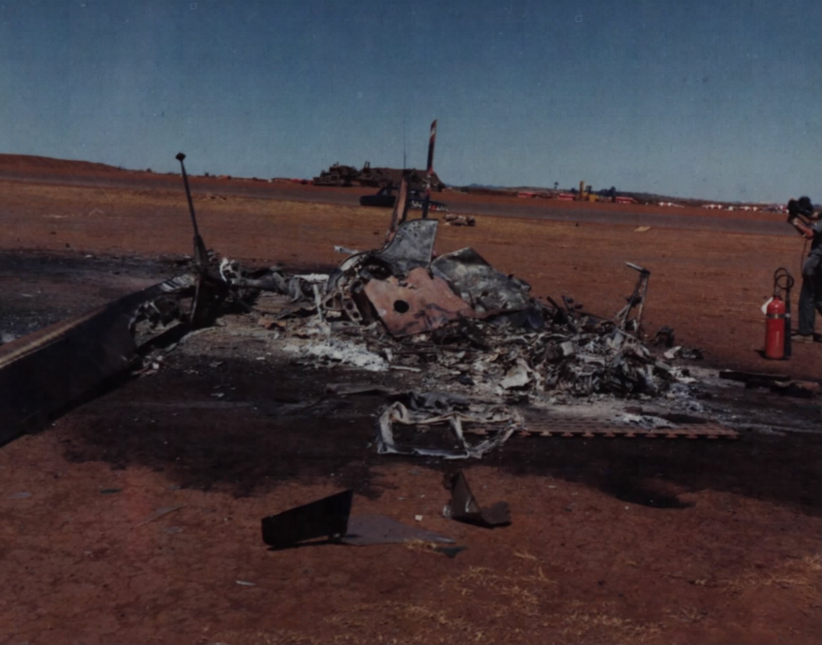 A wrecked helicopter on an airfield