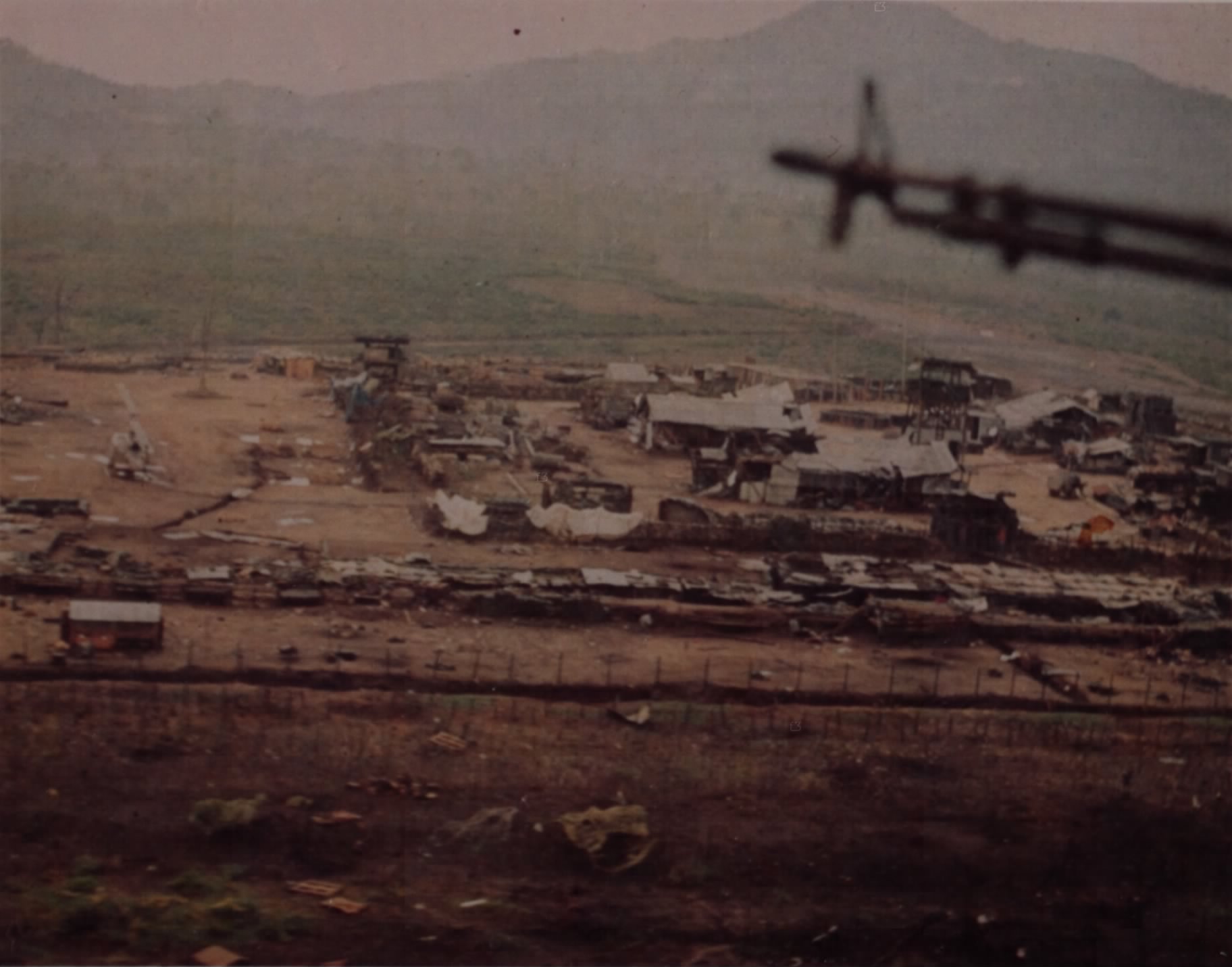 Aerial view of a battered camp of bunkers and trenches in a river valley