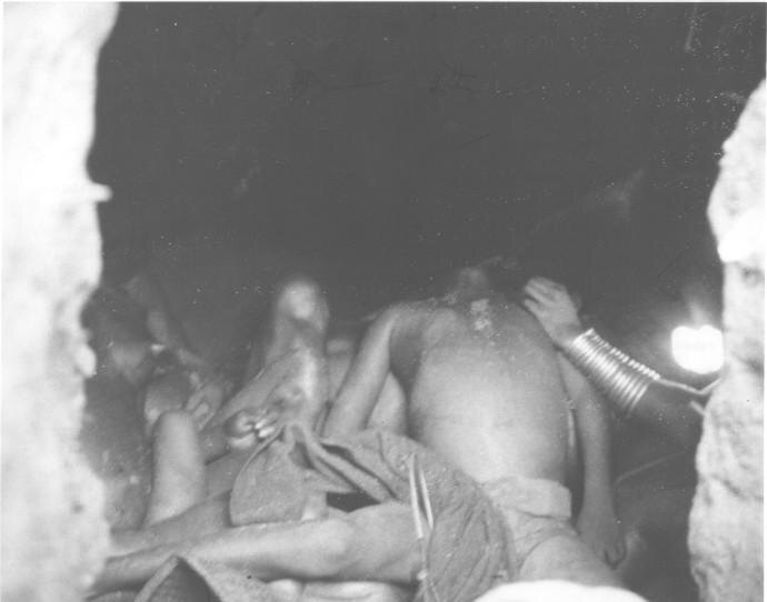 Bodies inside a dark earth shelter, a lamp lighting the opening