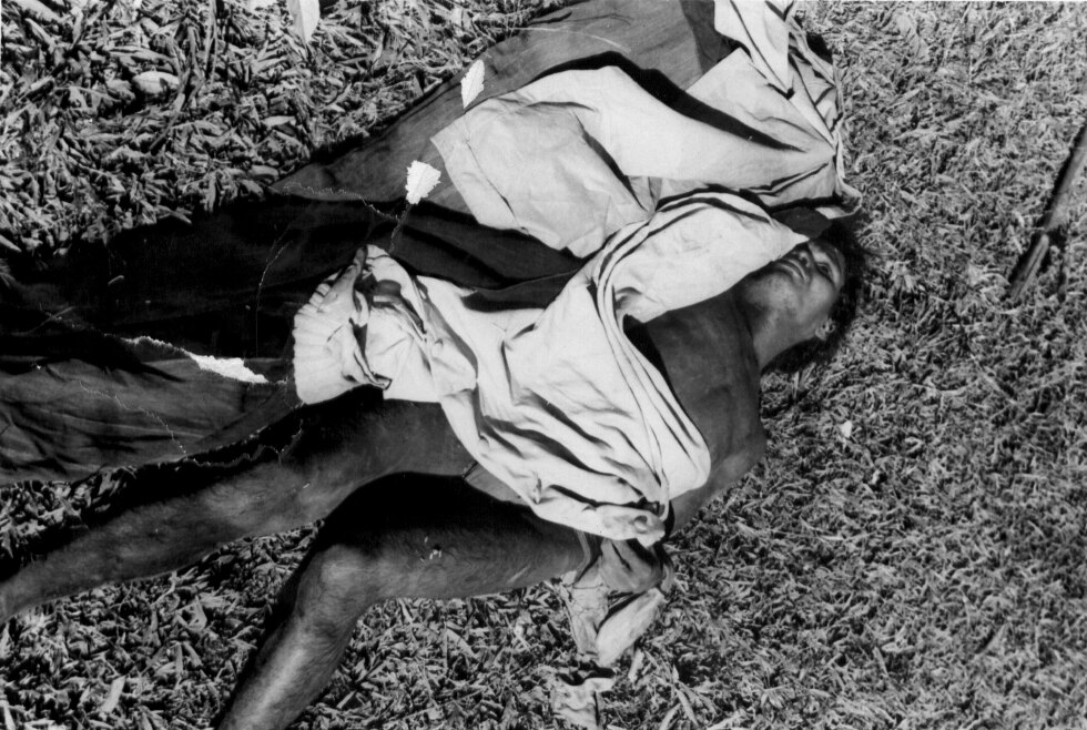 The body of a man lying on the grass with a cloth over him