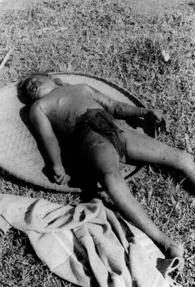 A child’s body lying on a woven tray on the grass, a blanket at its feet