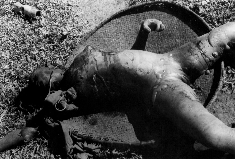 The burned body of a woman lying across a woven tray
