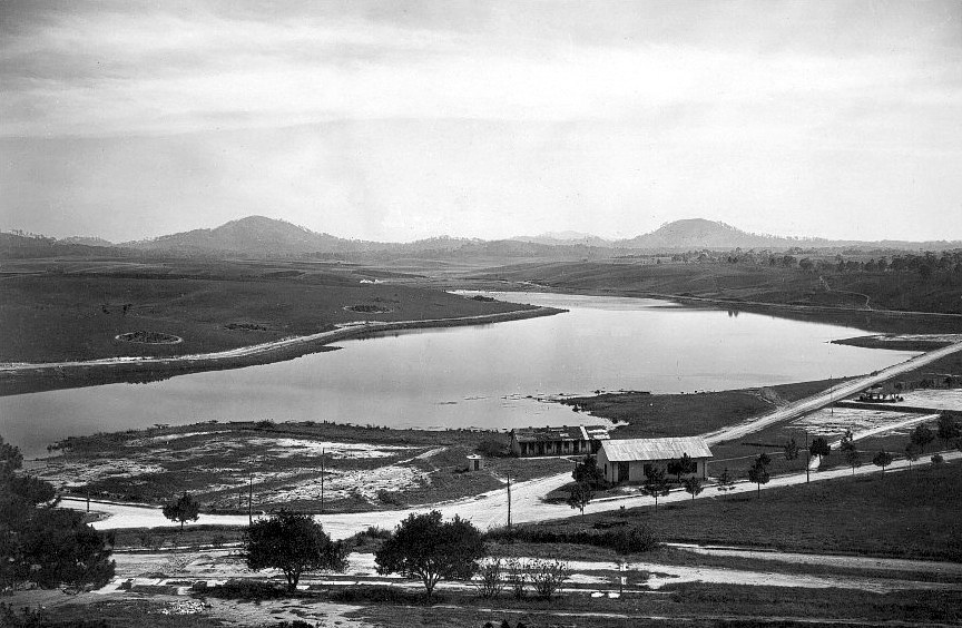 An old photograph of a lake with a few buildings on its shore