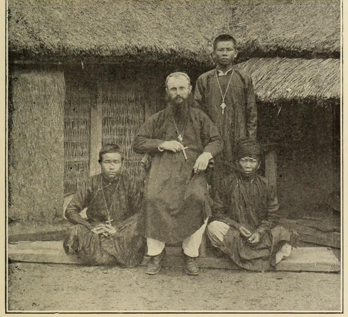 An engraving of a bearded priest seated in front of a bamboo house with three highland men