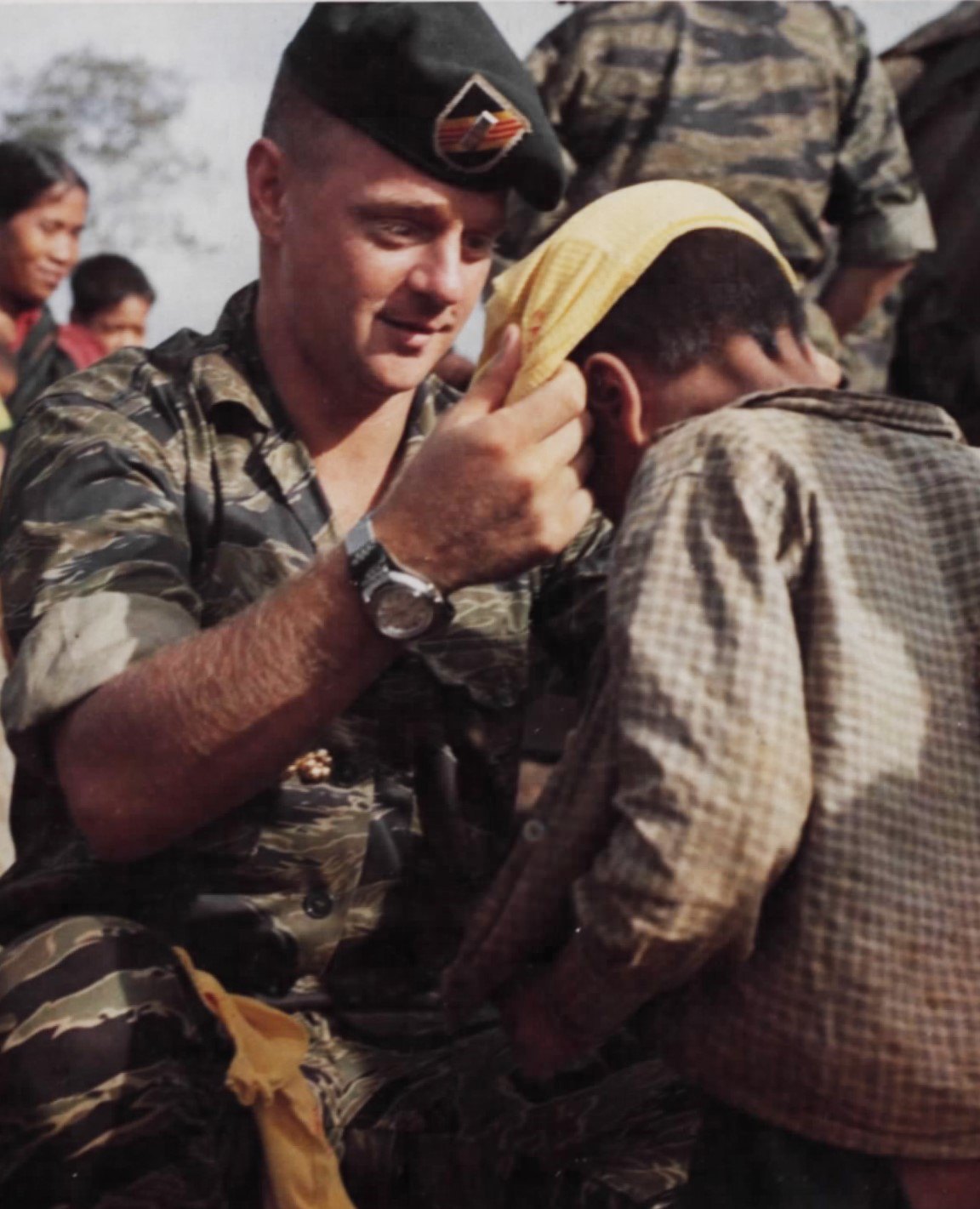 An American officer helping a small highland boy put on a t-shirt