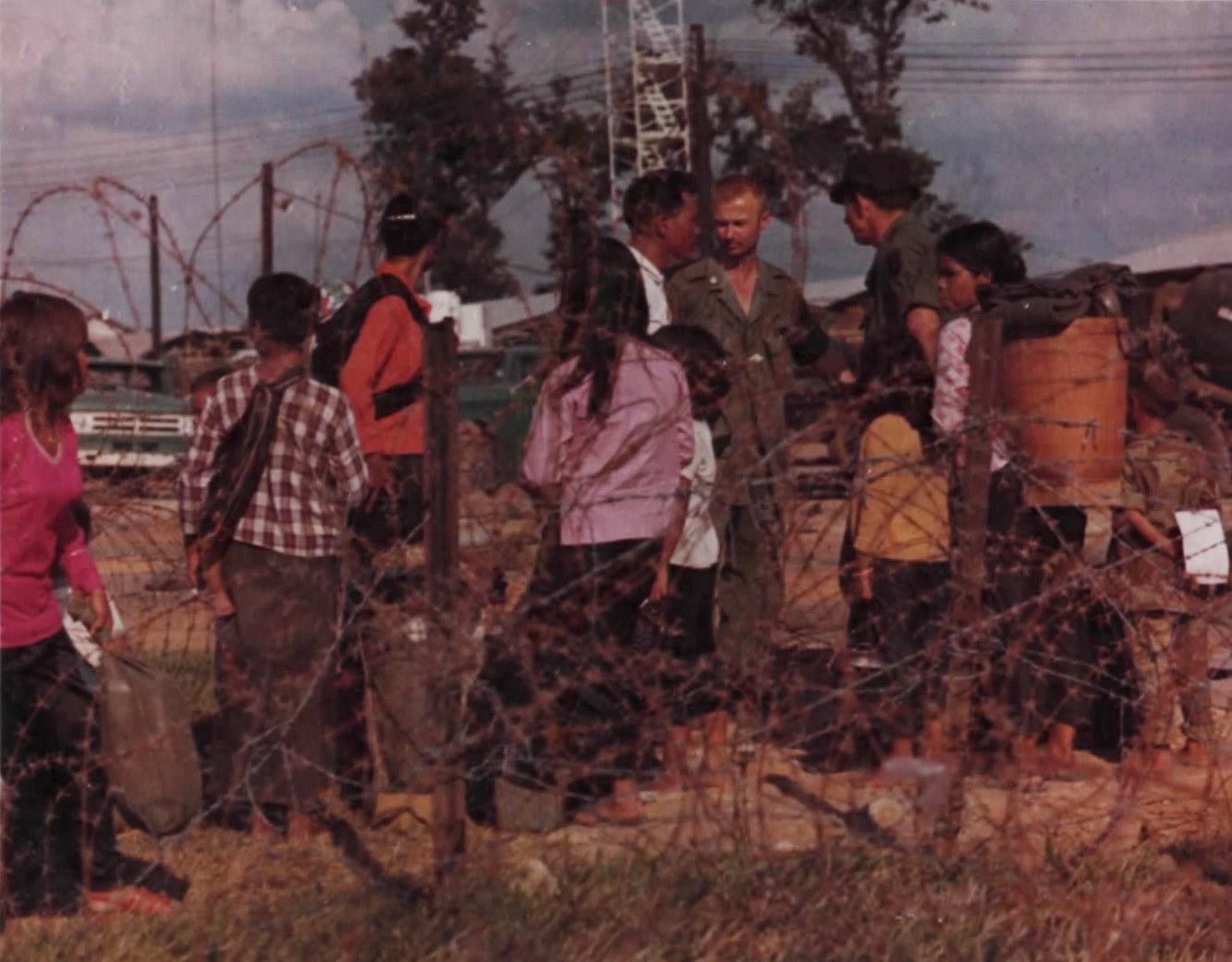 Highland women and children with bundles beside American advisers at an airfield