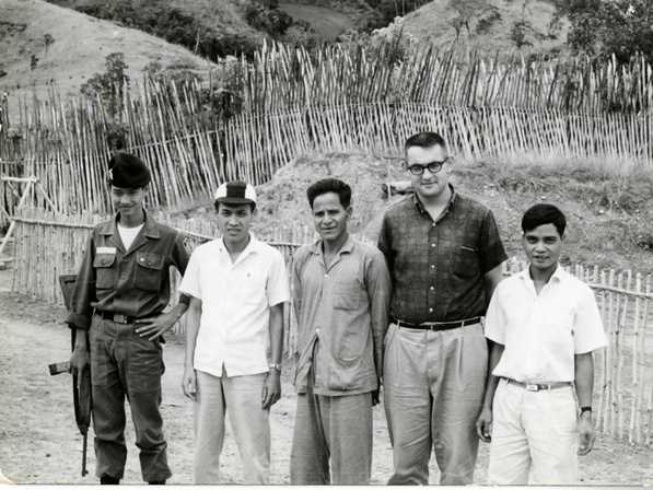 Five men standing in front of a bamboo fence in a highland hamlet