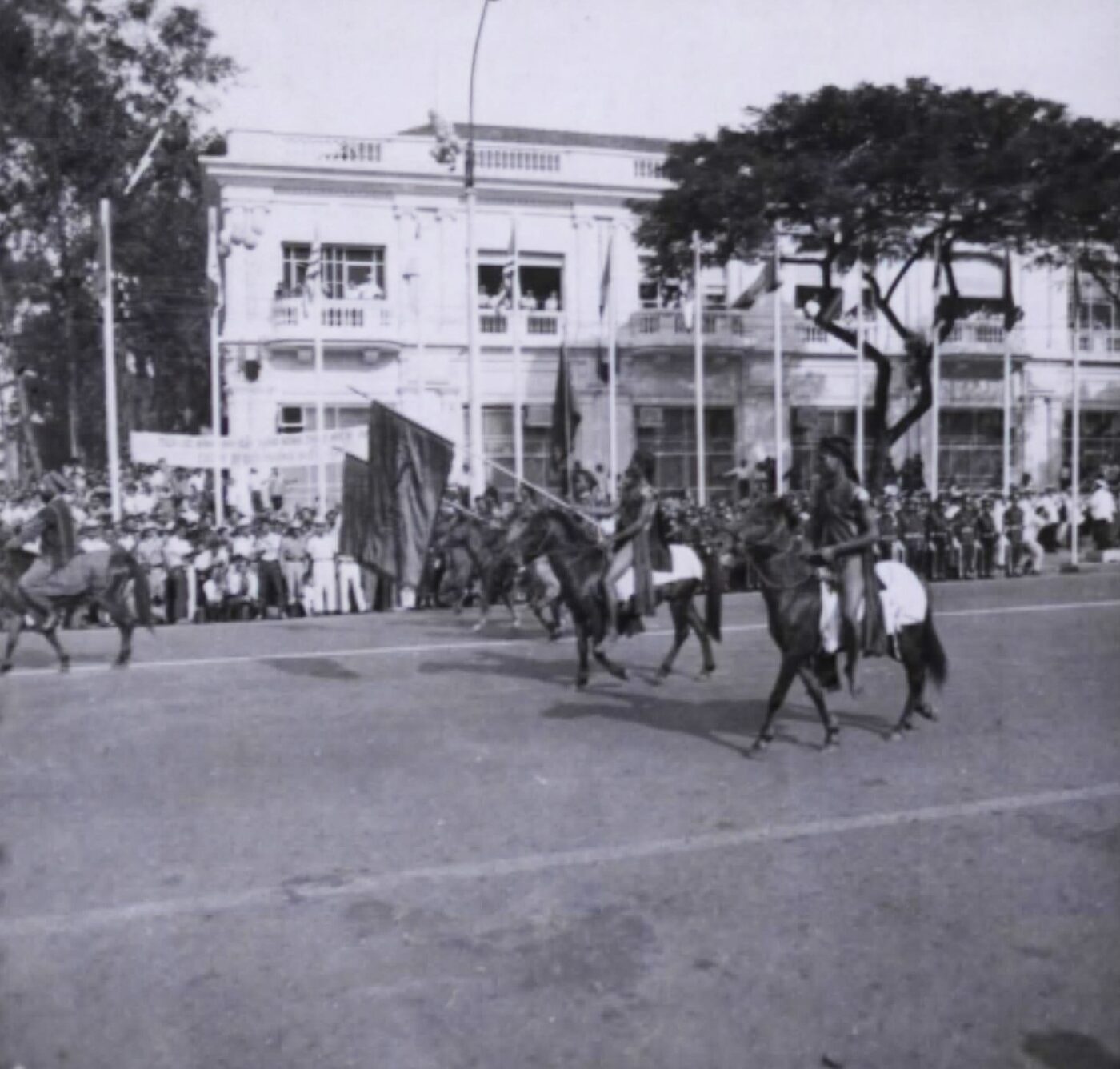 Highland men on horseback in traditional dress riding in a parade down a city street