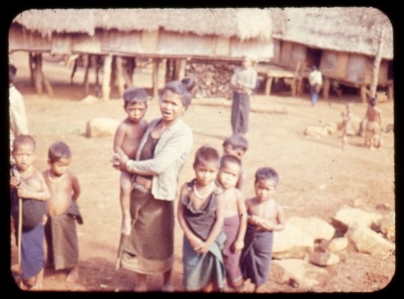 Highland villagers standing outside a house of thatch and timber
