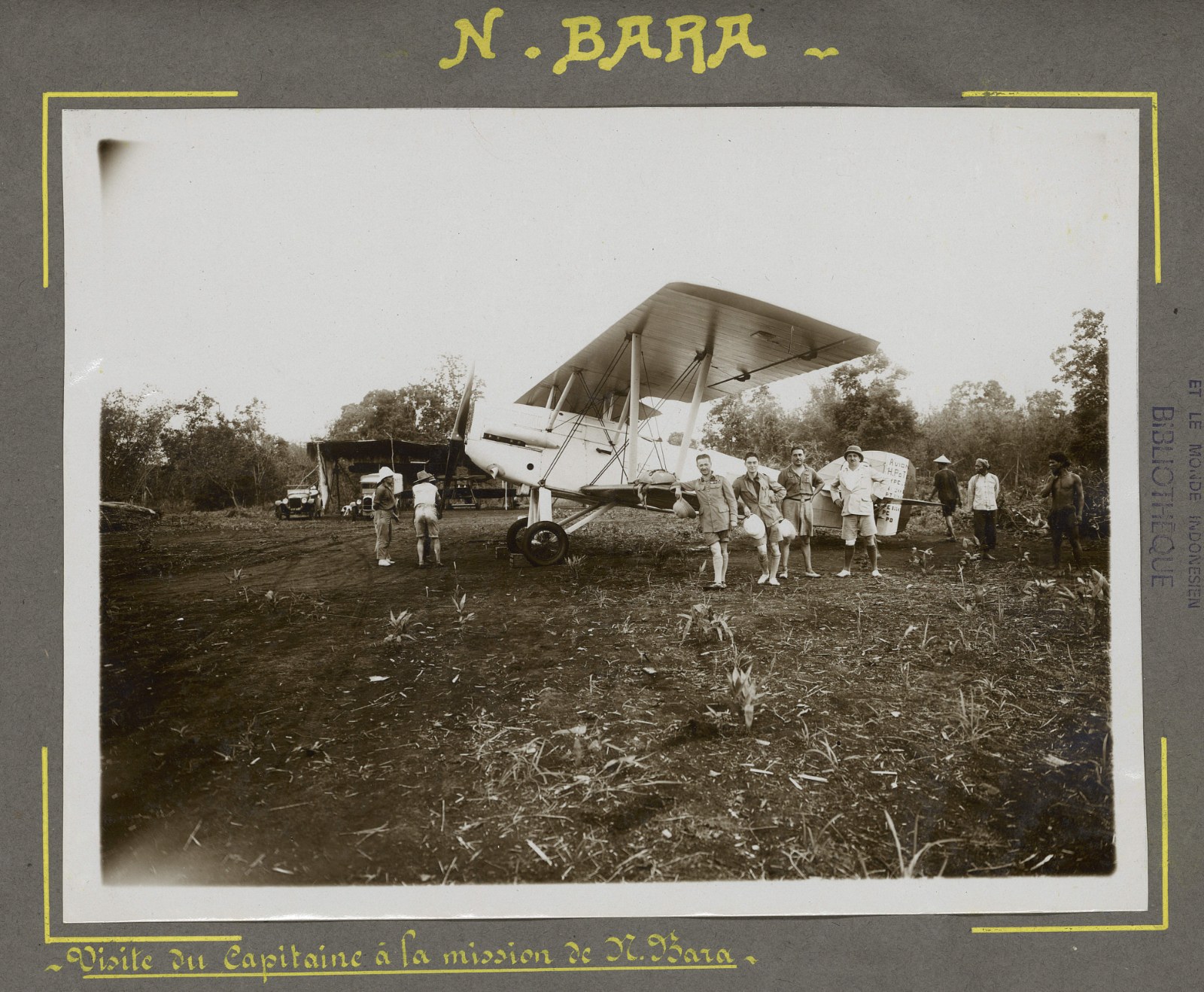 French officers in uniform standing before a biplane