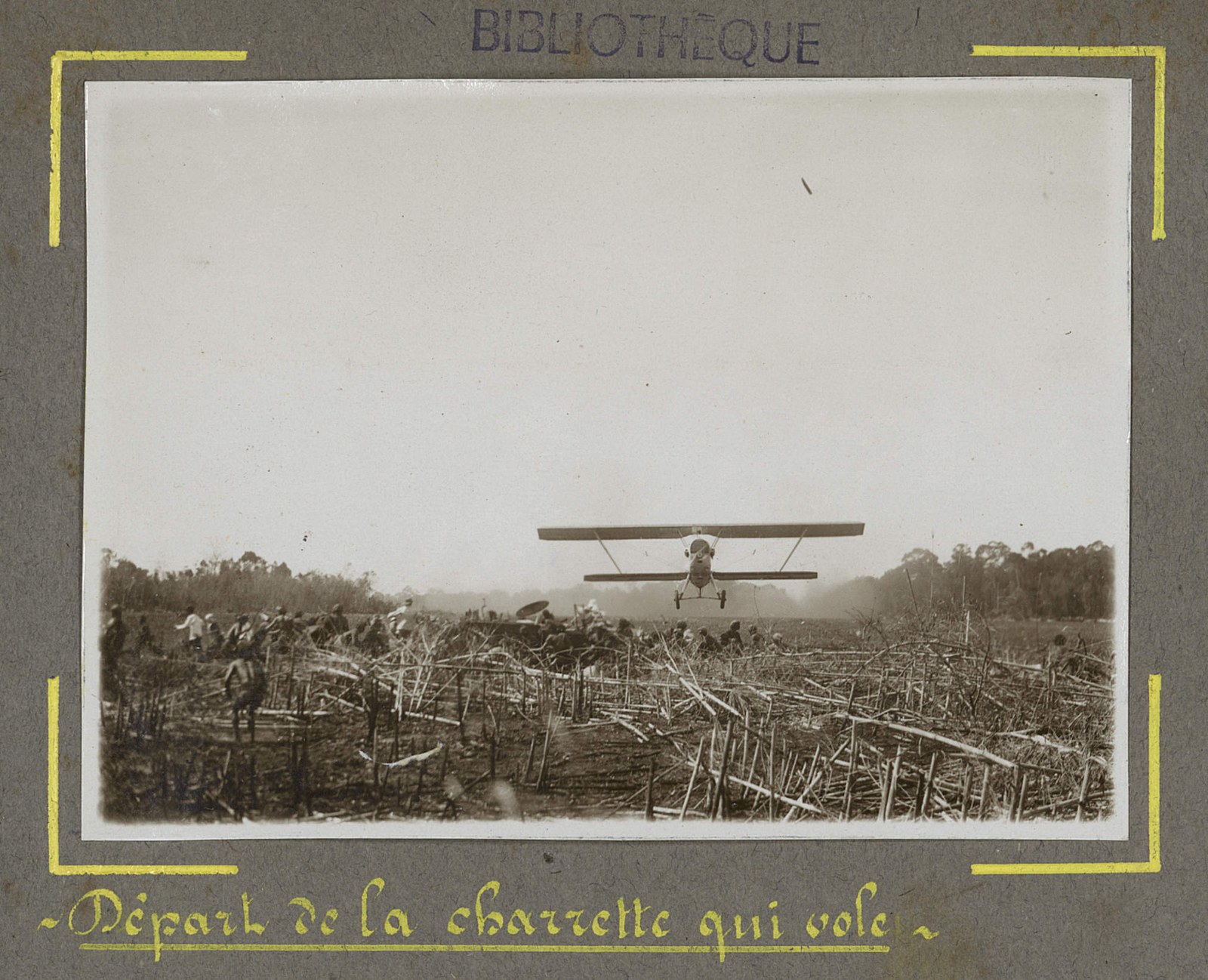 A biplane taking off from a grass strip in a cloud of dust