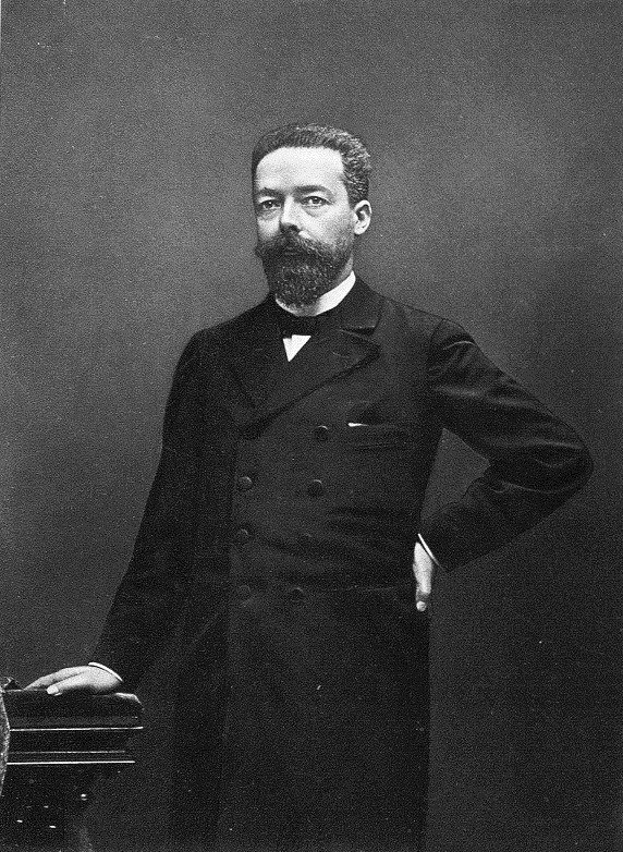 A studio portrait of a bearded man in a frock coat