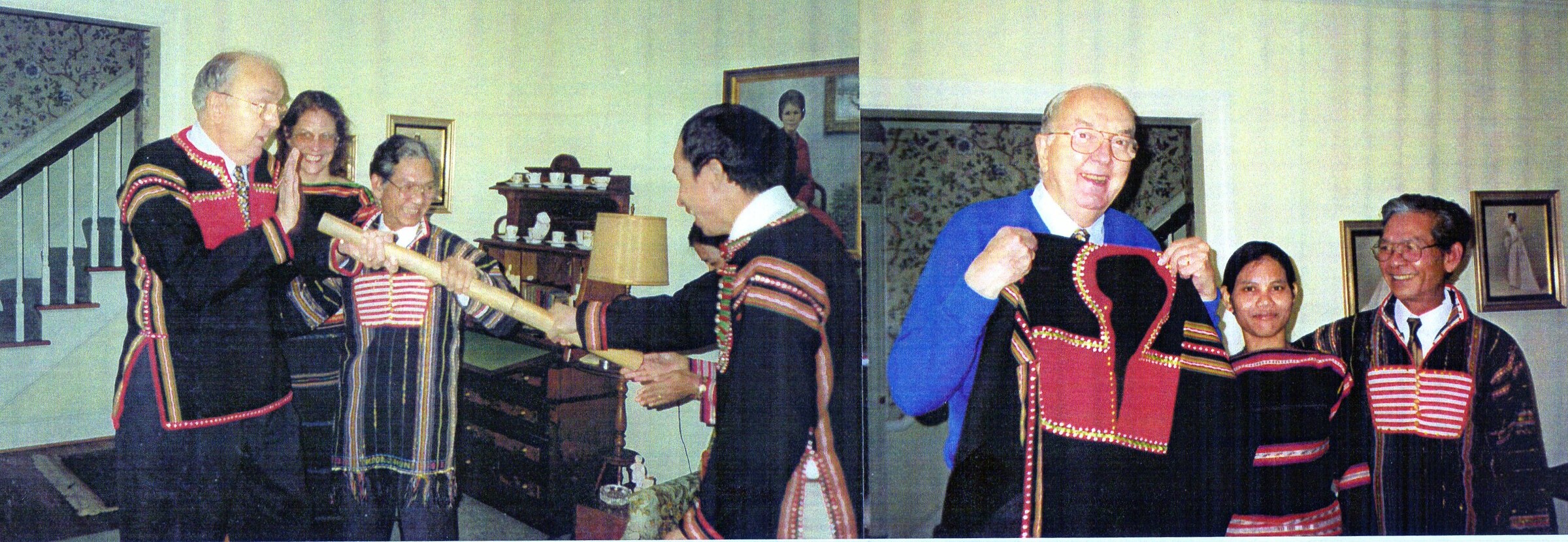 An older man in a woven highland jacket laughs with a group of highland men and women, one of them playing a gong