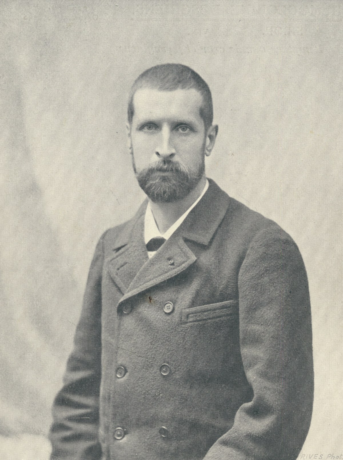 A photographic portrait of a young man with a short beard