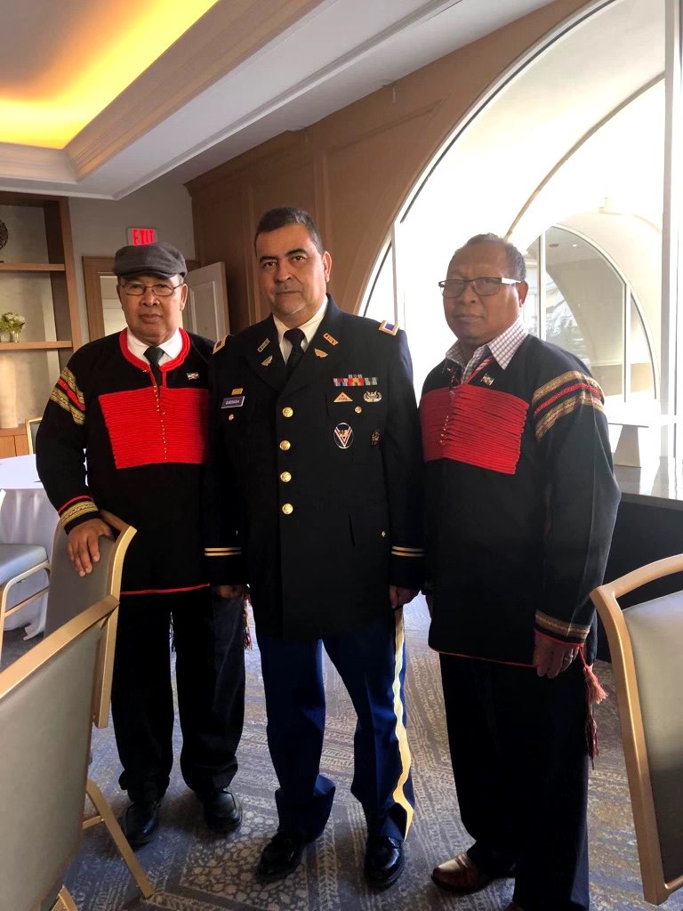 Two Dega delegates in traditional dress standing with a United States Army officer in uniform