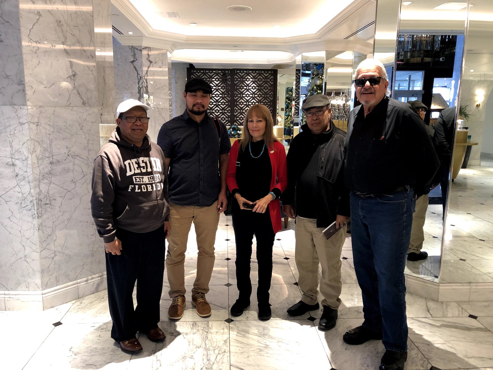 Five people standing together in a marble hotel lobby