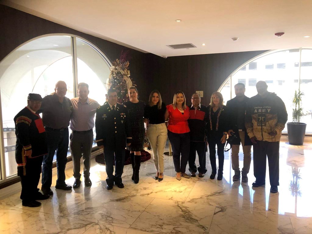 Delegates and conference attendees standing in a line in a hotel lobby beside a Christmas tree