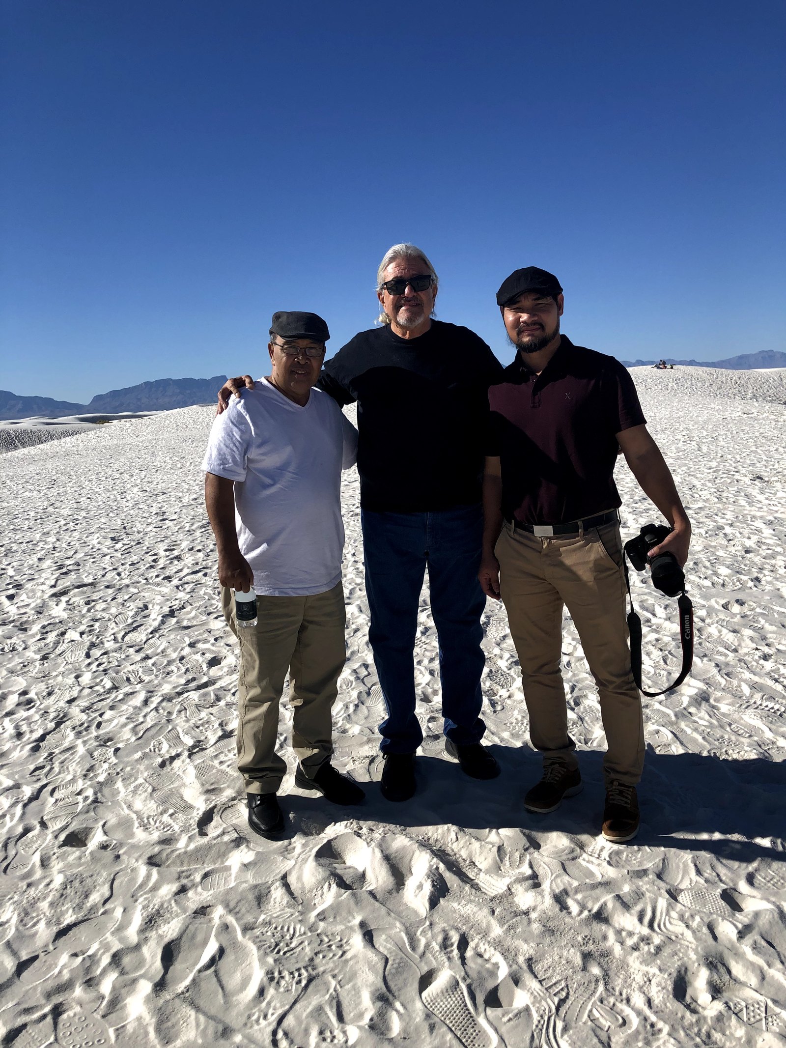 Three people standing with arms around each other on the white dunes