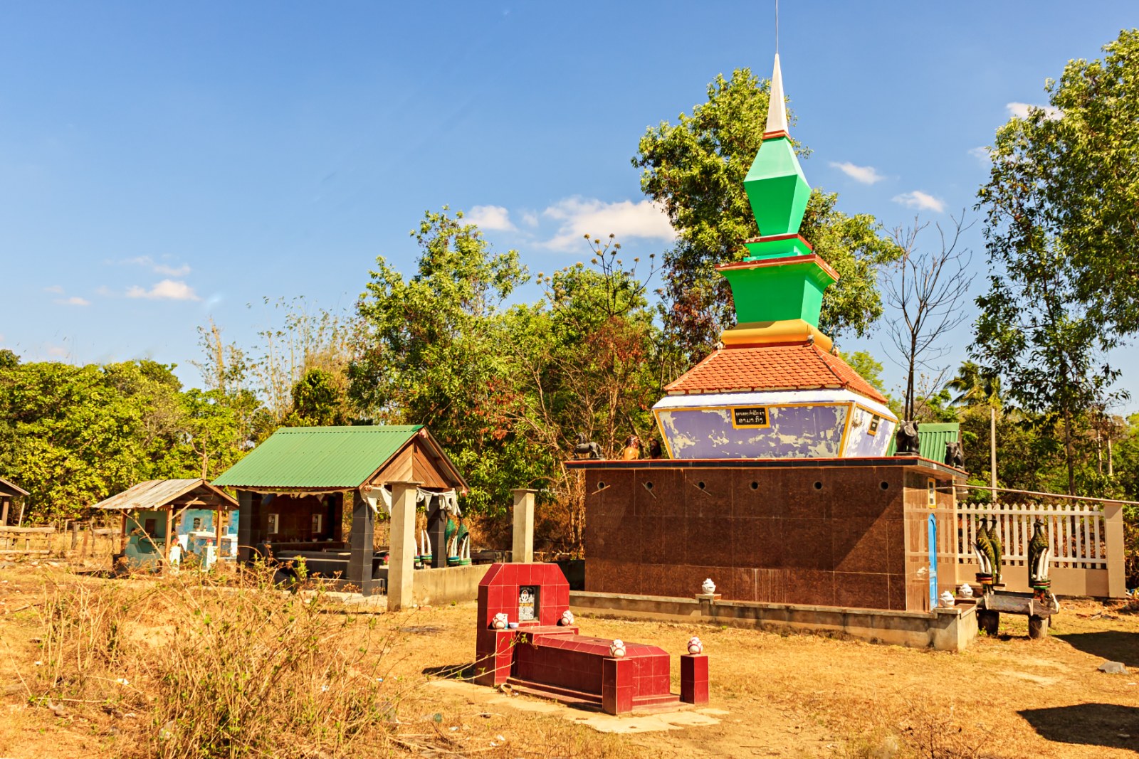 A brightly painted tomb with a pointed spire among trees