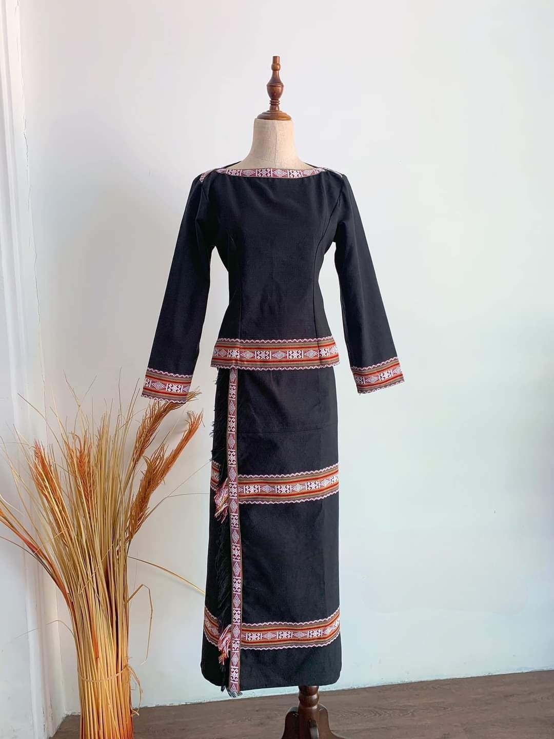 A Bahnar woman’s dark blouse and skirt with bright red patterned bands, photographed today