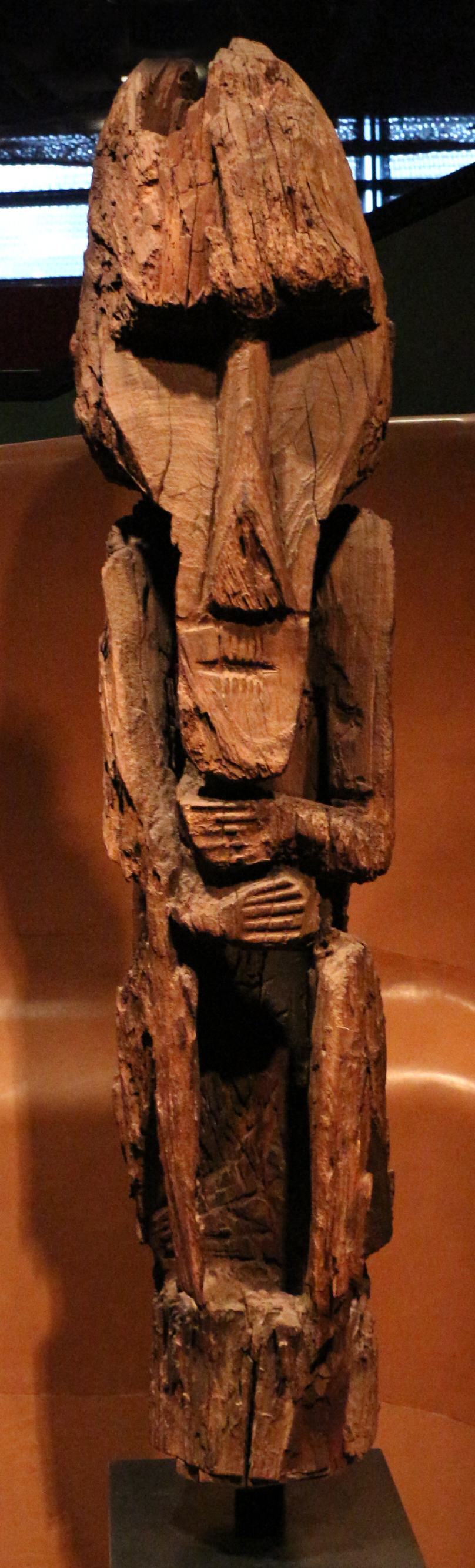 A weathered carved wooden figure with its hands folded