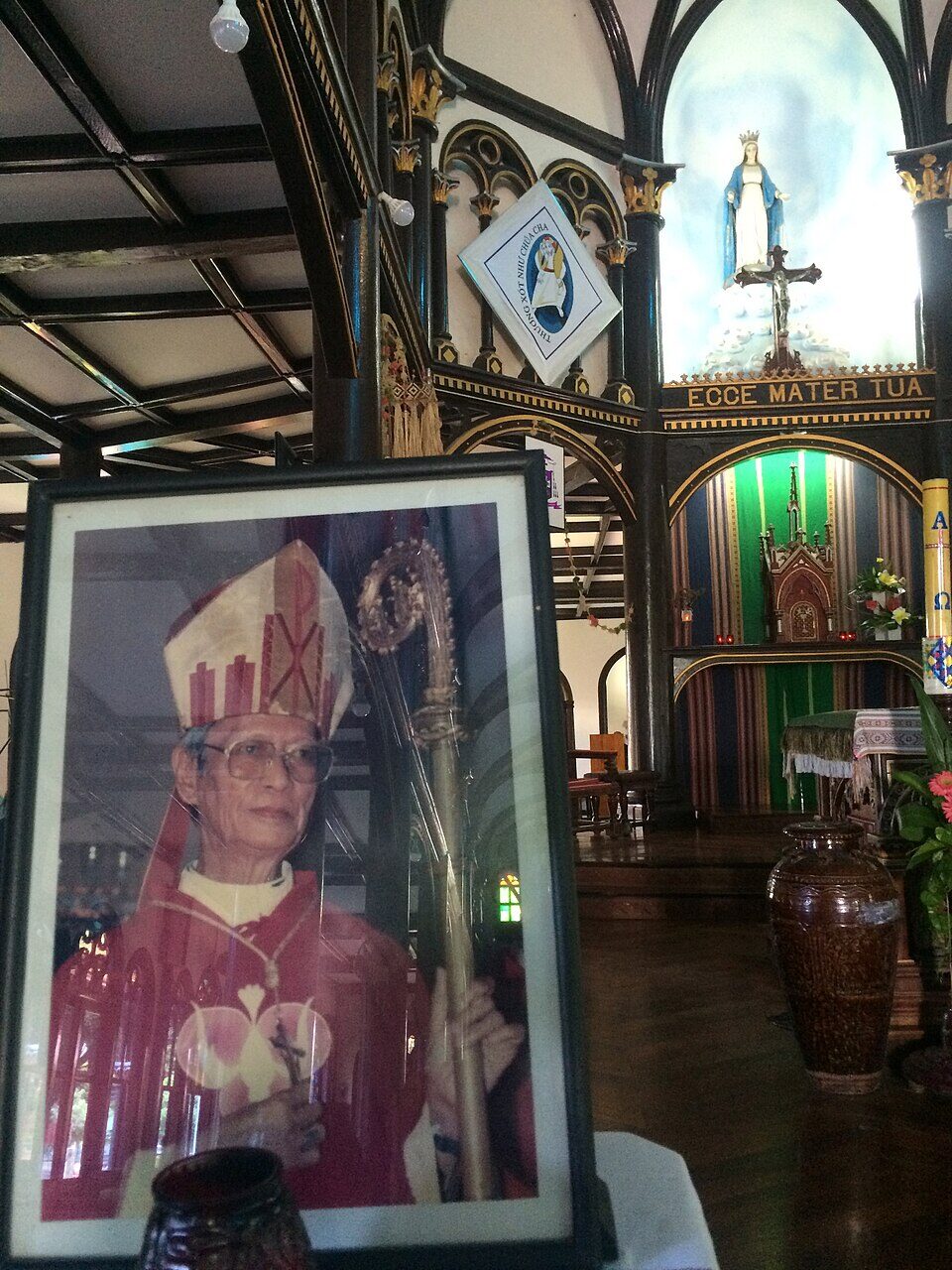 A framed portrait of a bishop in vestments, standing inside a church