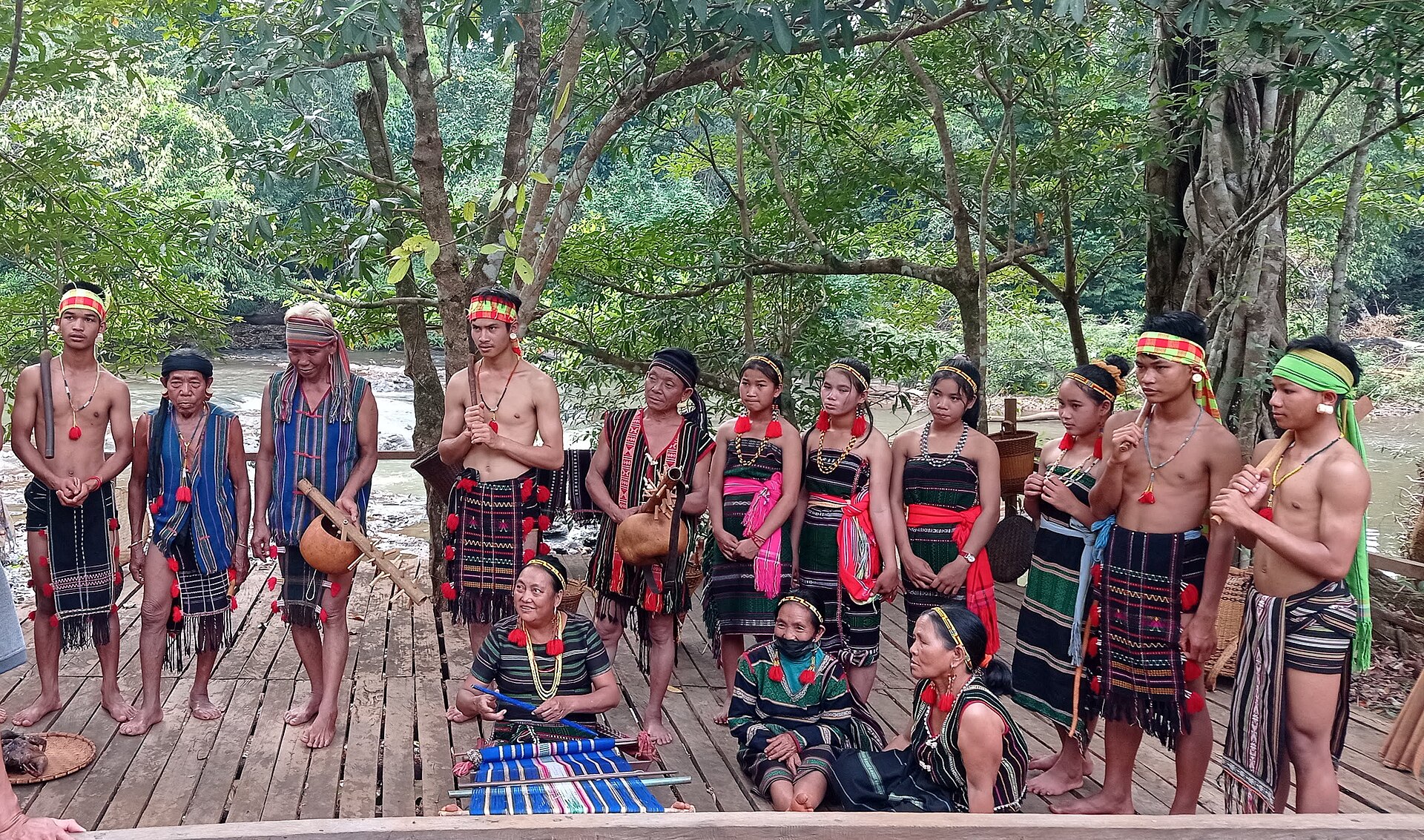 A group of Bunong men and women in traditional dress standing on a wooden platform