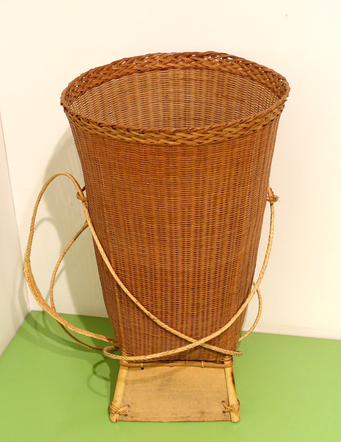 A tall woven carrying basket with straps