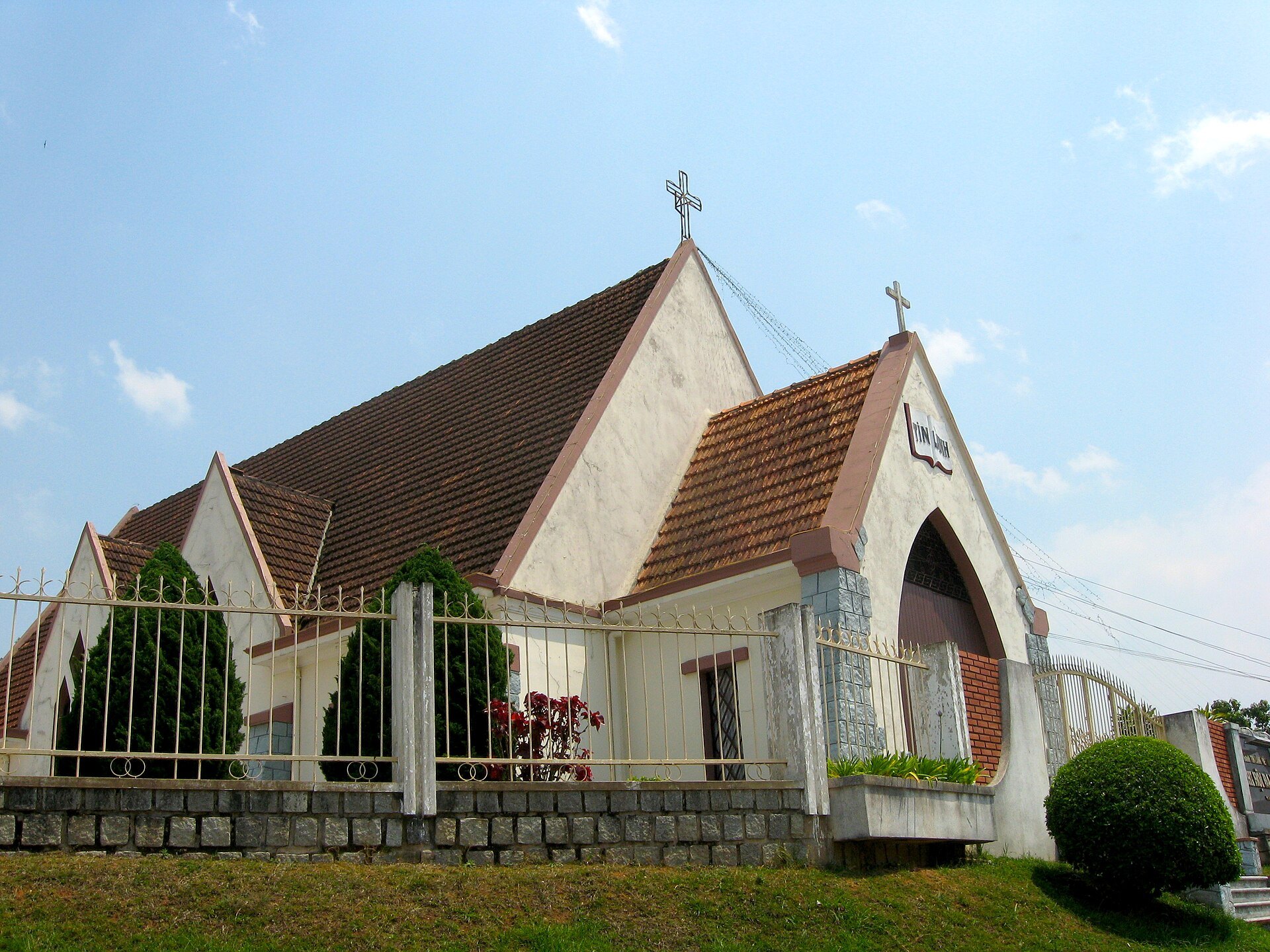 A white church with a tall pointed steeple behind a low fence