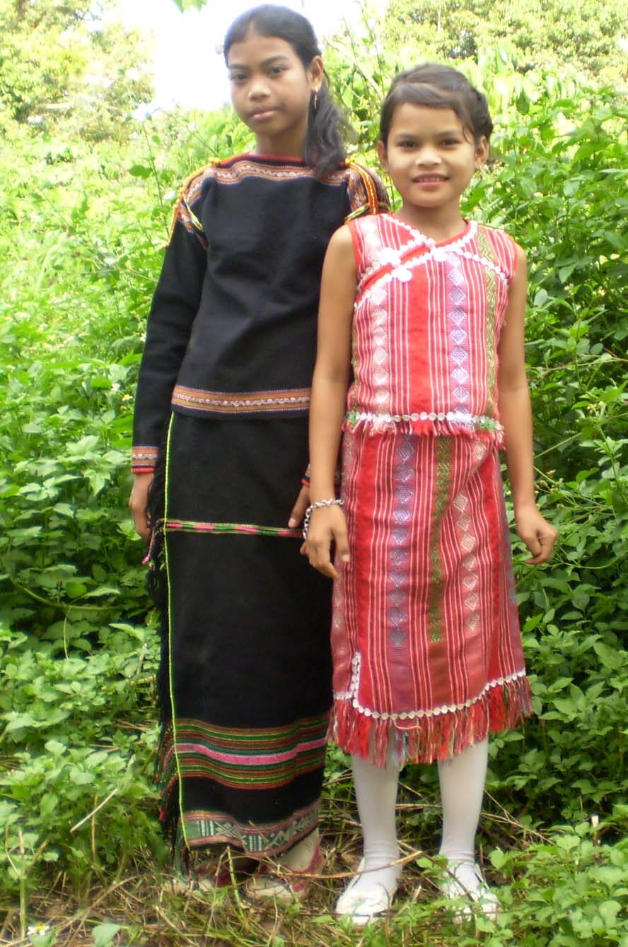 Two Ede girls in woven dress standing in long grass