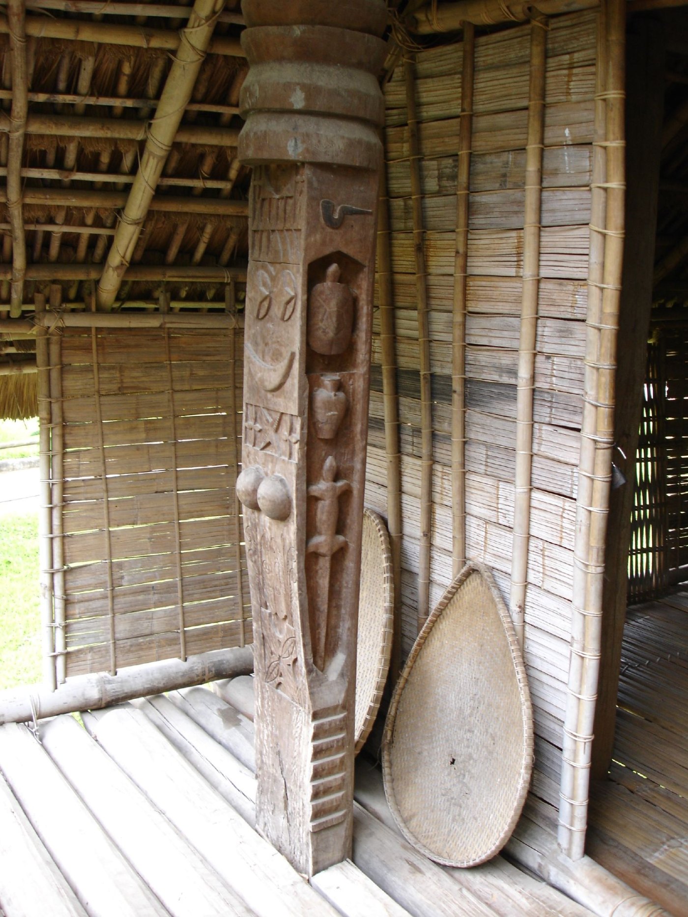 The long interior of a Rhade longhouse with a wooden floor and a row of posts