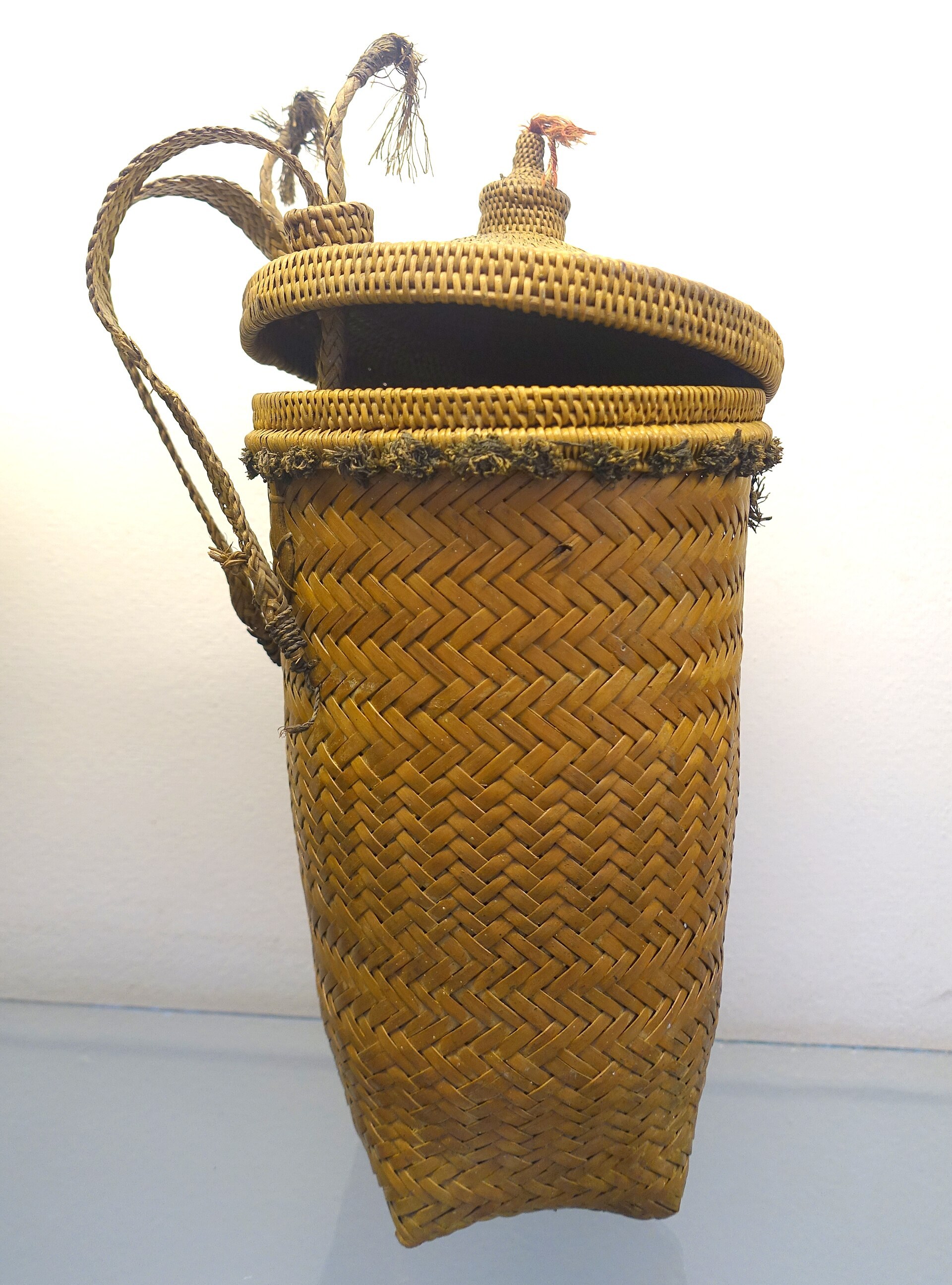 A woven quiver with a lid and a carrying strap, for crossbow arrows