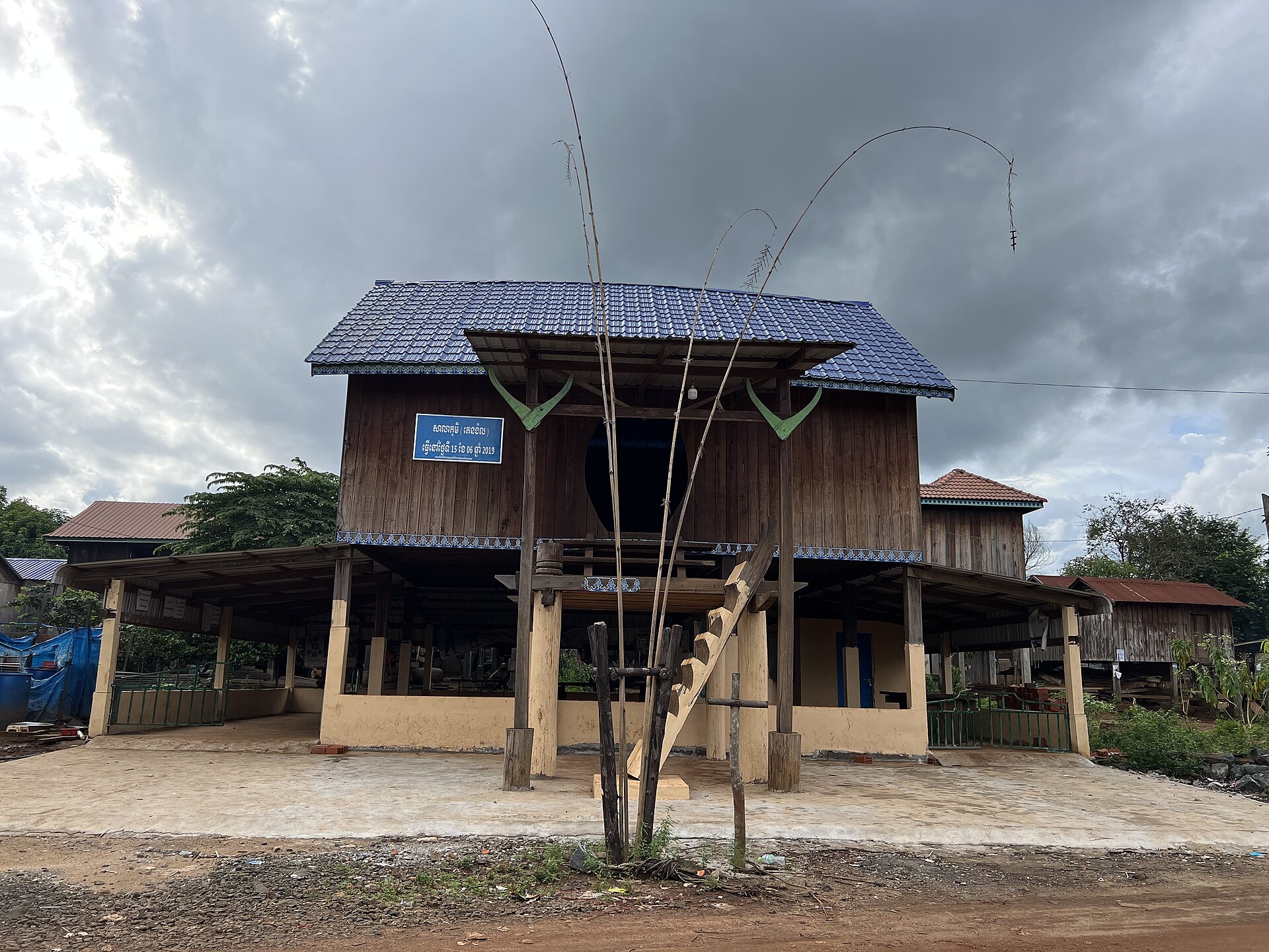 A raised wooden community hall with a steep roof