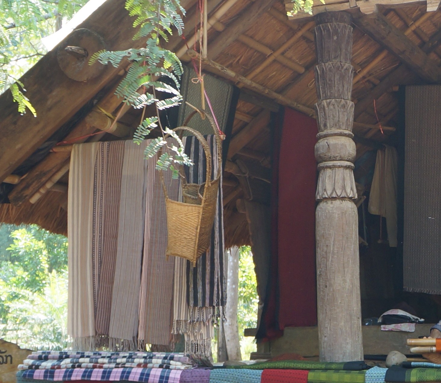 A woven basket hung beside carved wooden posts in a Katu house