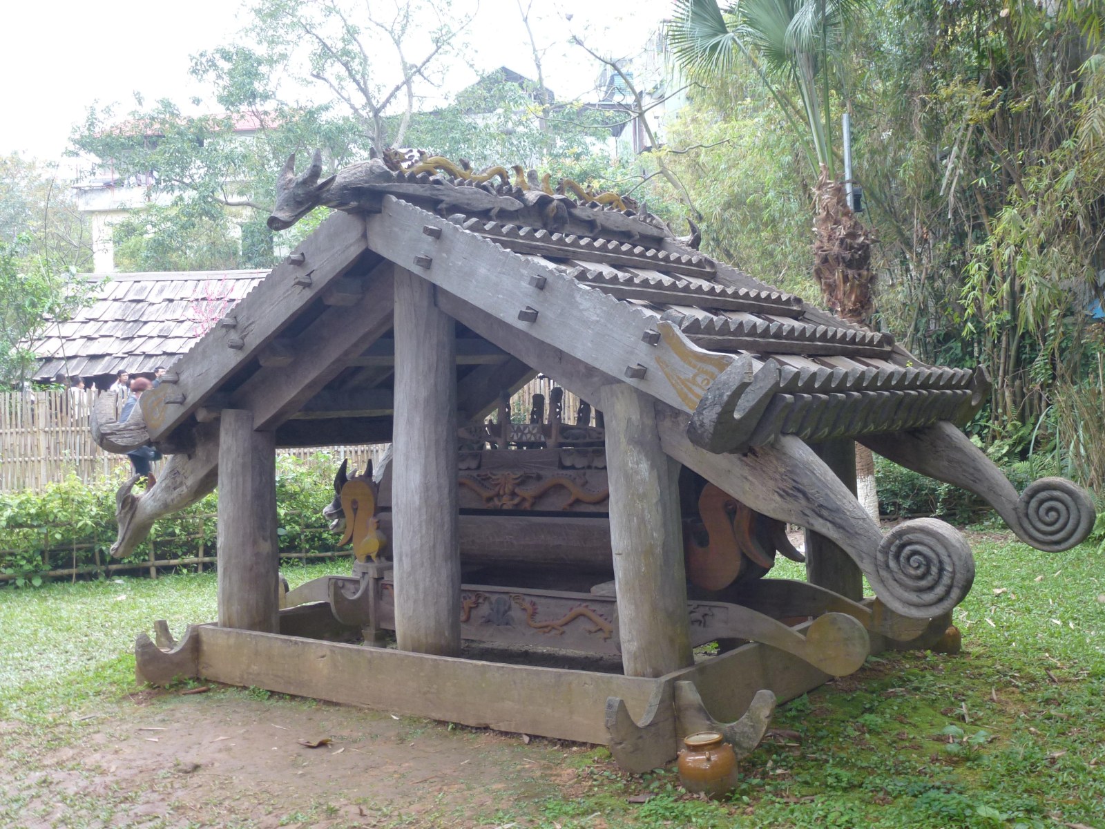 A carved wooden tomb house with a roof and figures