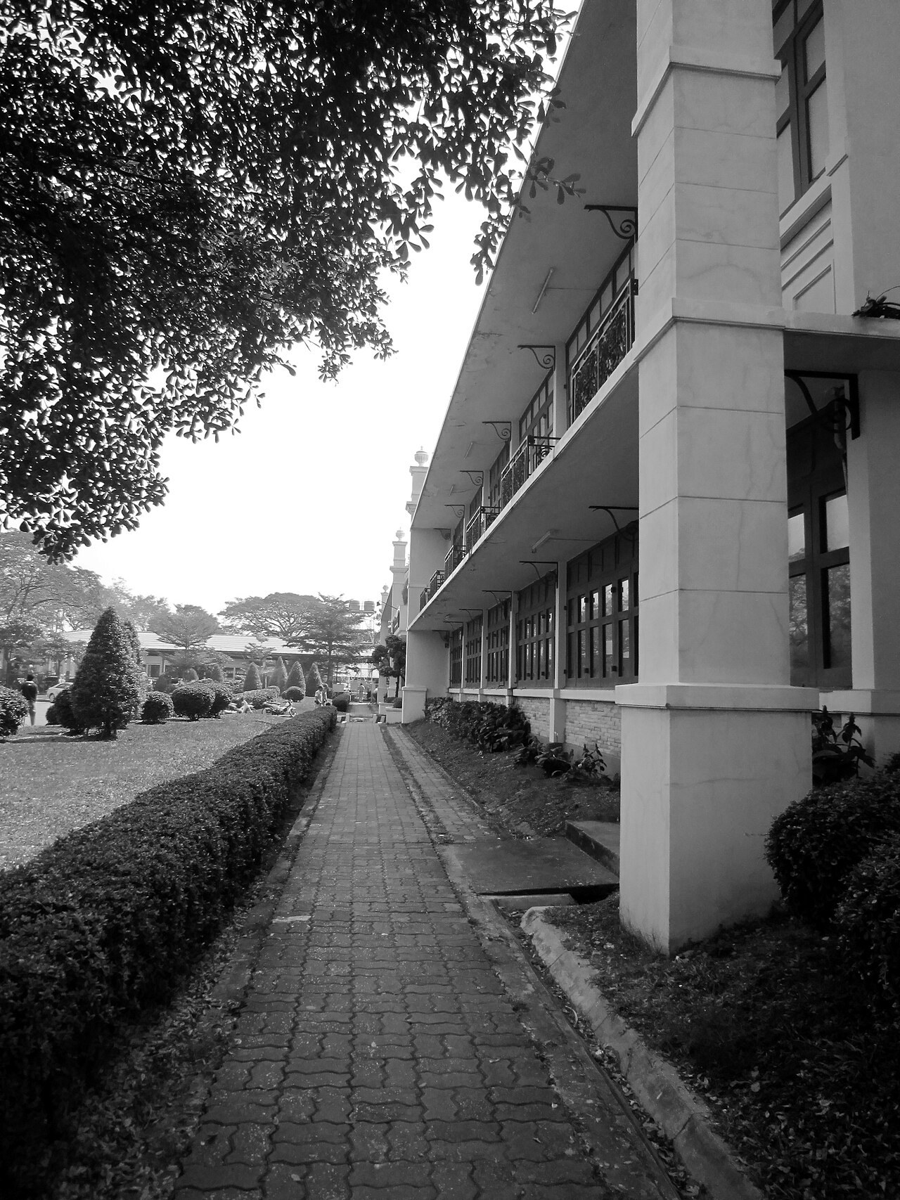 A black-and-white photograph of a long, empty walkway beside a prison building