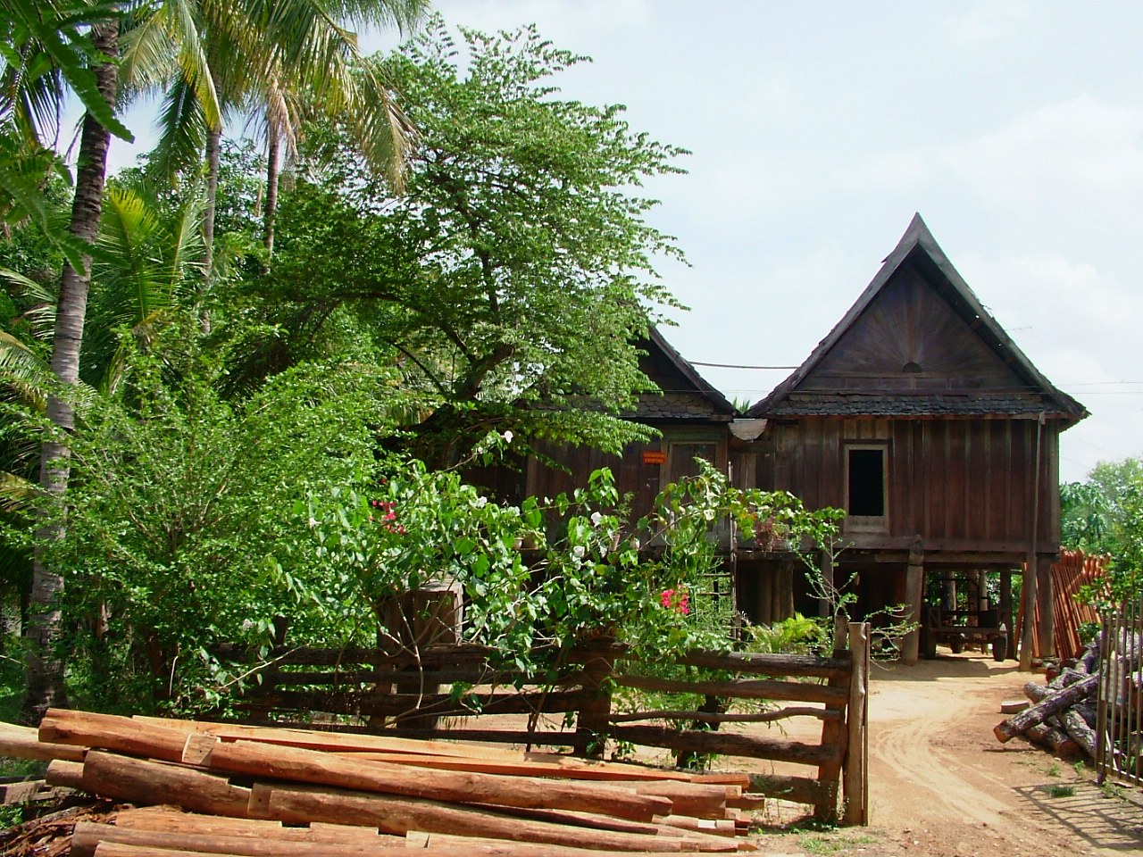 An old wooden house on tall stilts with a steep tiled roof among trees