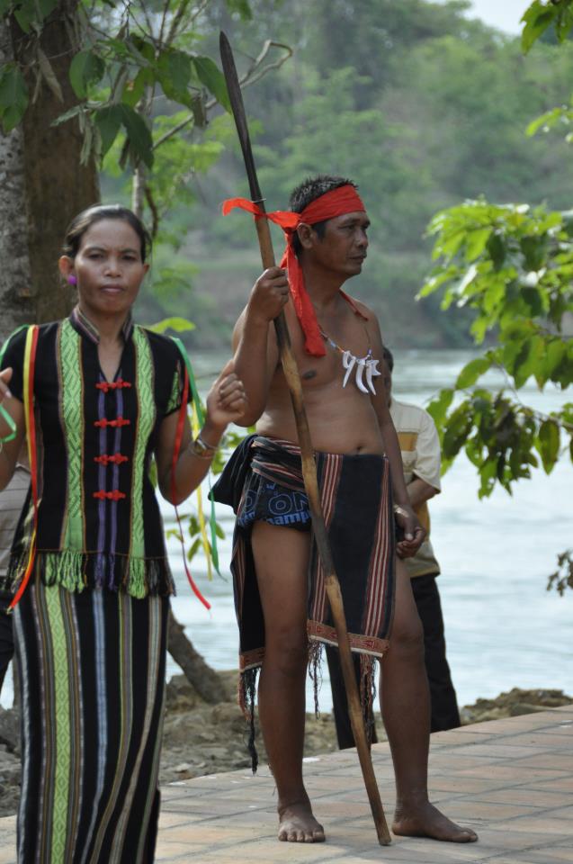 Mnong men in ceremonial dress holding spears