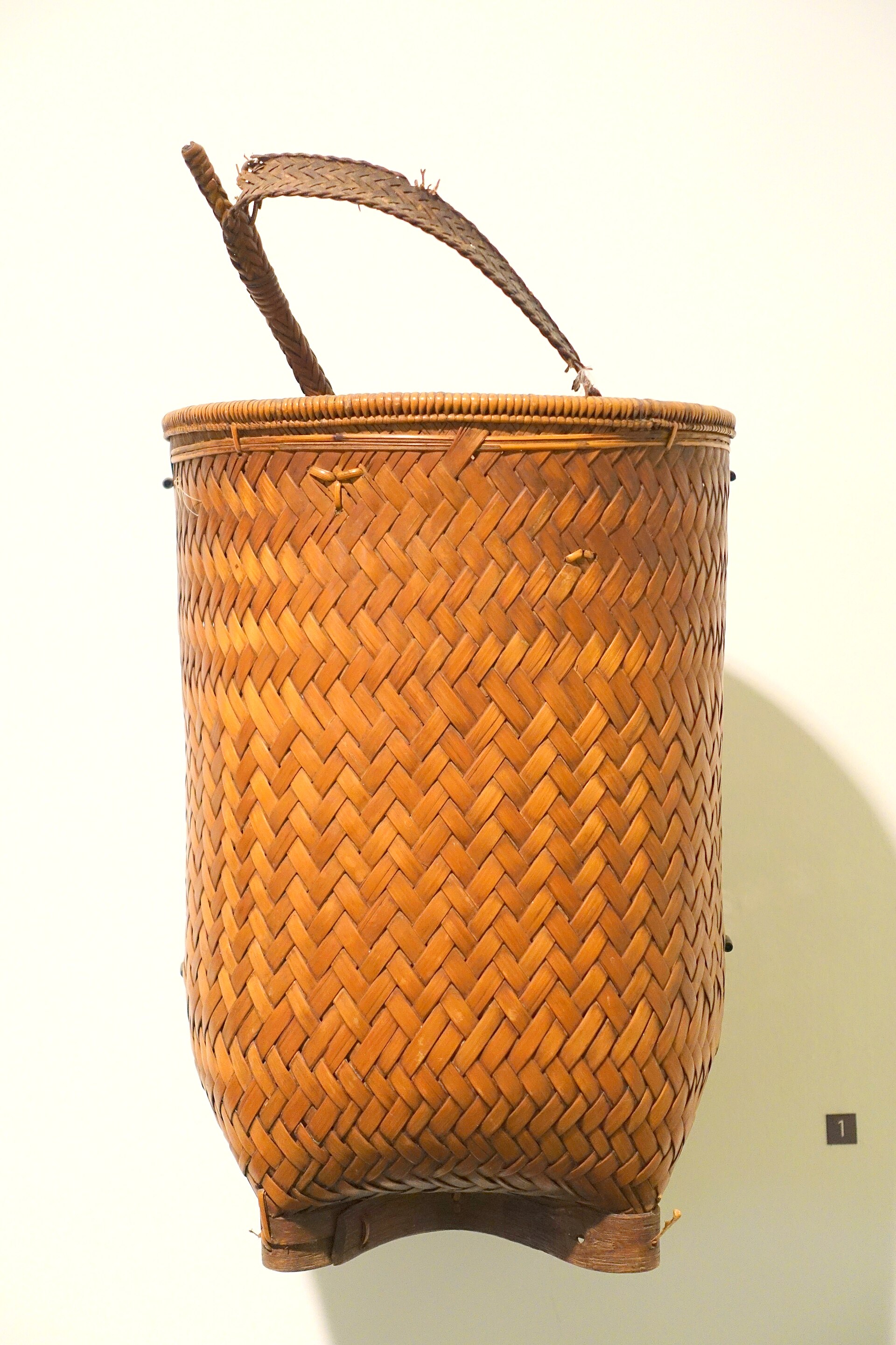 A tall woven harvest basket with a strap