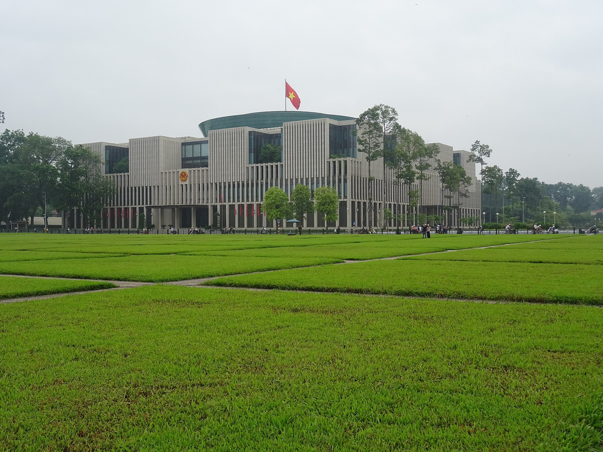 A large modern government building with a curved glass front and a wide plaza