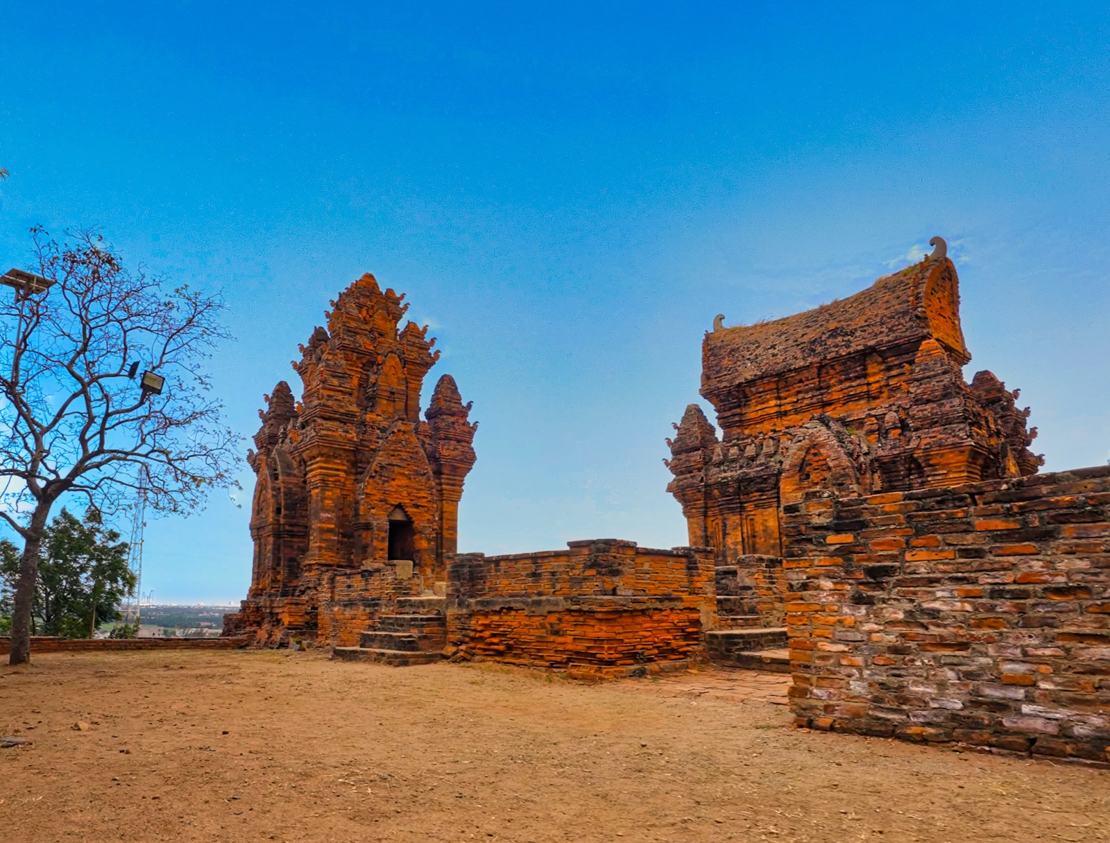 Three brick Cham towers on a hill against a blue sky