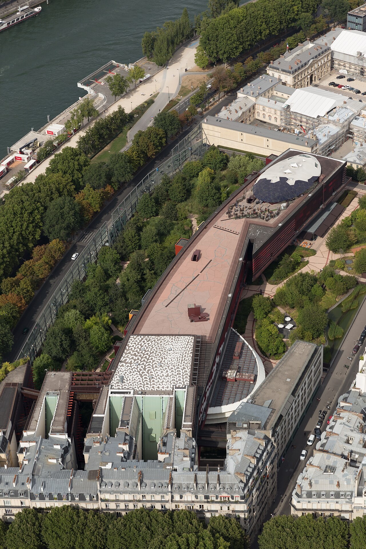 The long curving museum building of the Quai Branly seen from high above, among gardens beside the Seine