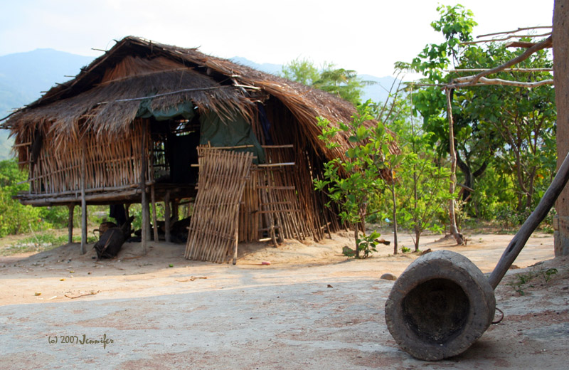 A raised thatched house with a wooden mortar in front