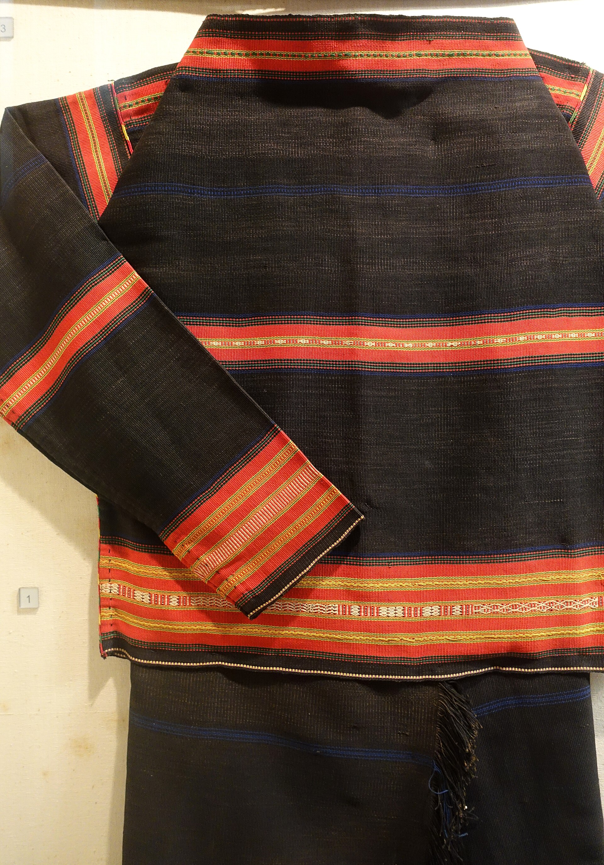 A dark Rhade blouse with bands of red at the sleeves and hem