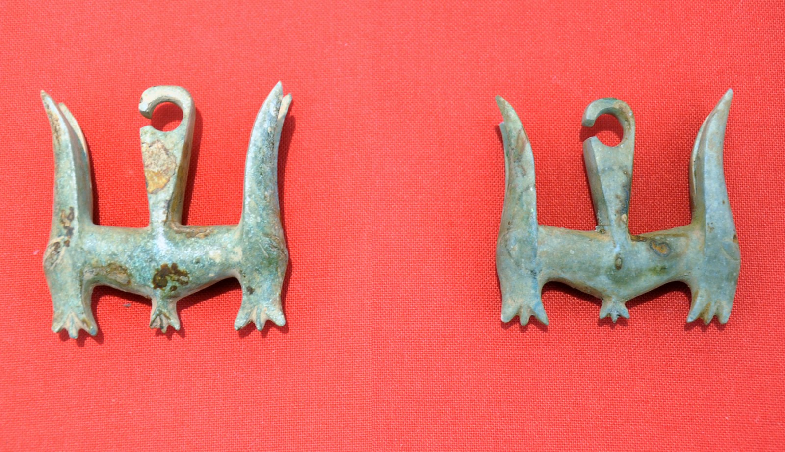 A pair of pale green stone ear ornaments in the form of two-headed animals