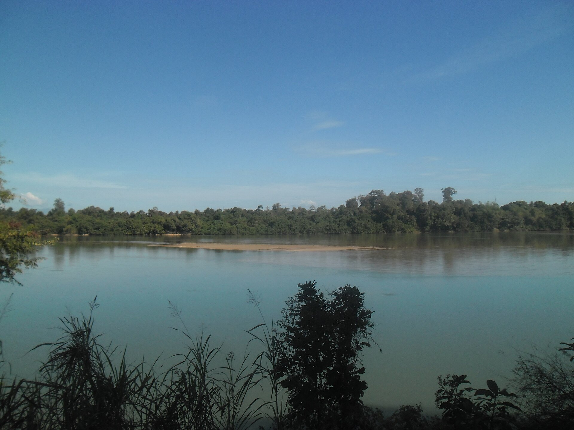 A broad calm river between low forested banks