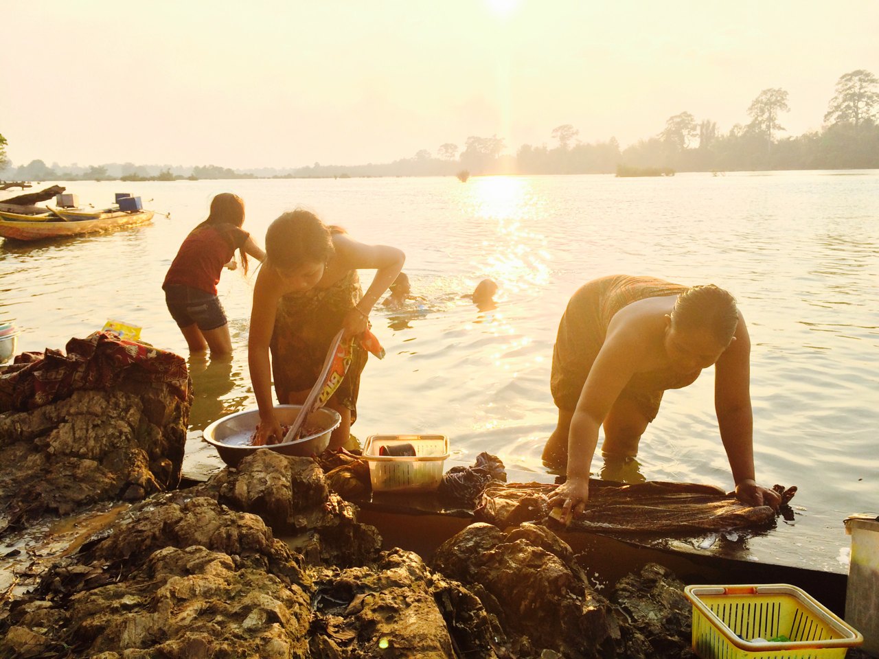 Women washing clothes on the bank of a wide river at sunset